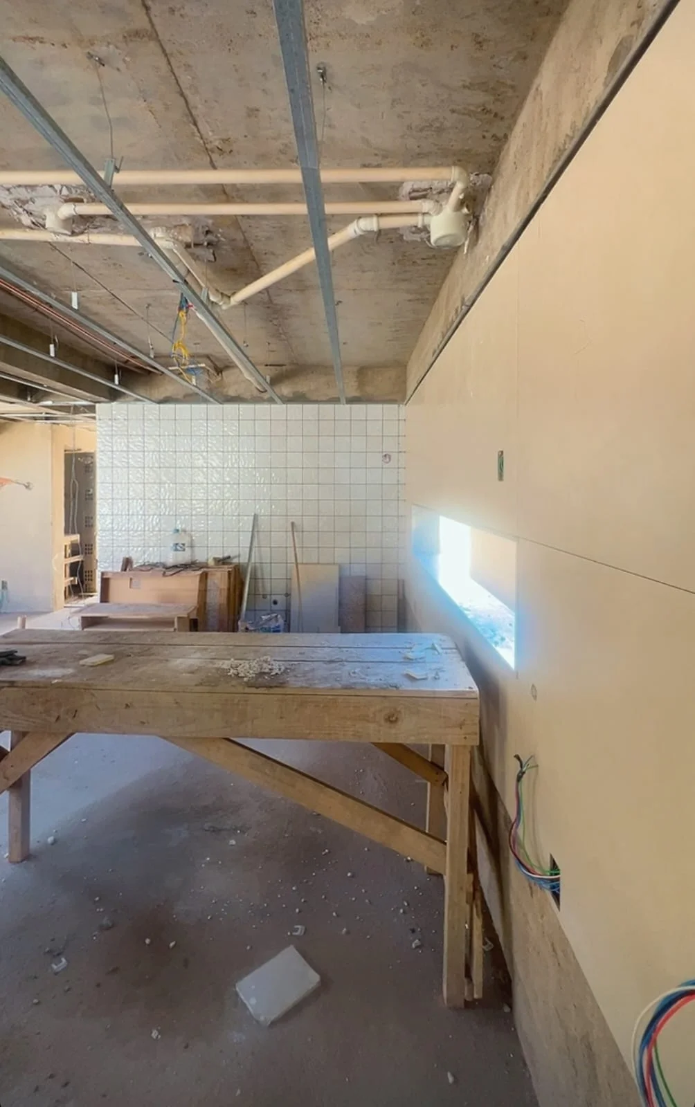 Obra em andamento, com instalações aparentes, paredes e bancada em execução.